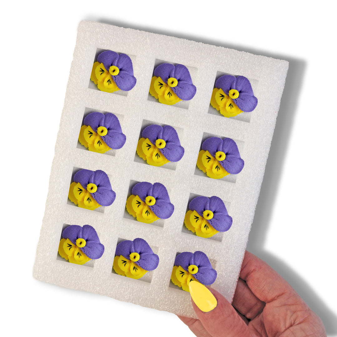 A set of 12 hand-piped Royal Icing Pansies, featuring beautiful purple and yellow petals. These decorations are freeze and bake stable, measuring .75" in size, and have a sweet vanilla flavor. Perfect for adding a touch of springtime cheer to your Mother's Day and spring-themed baked goods.