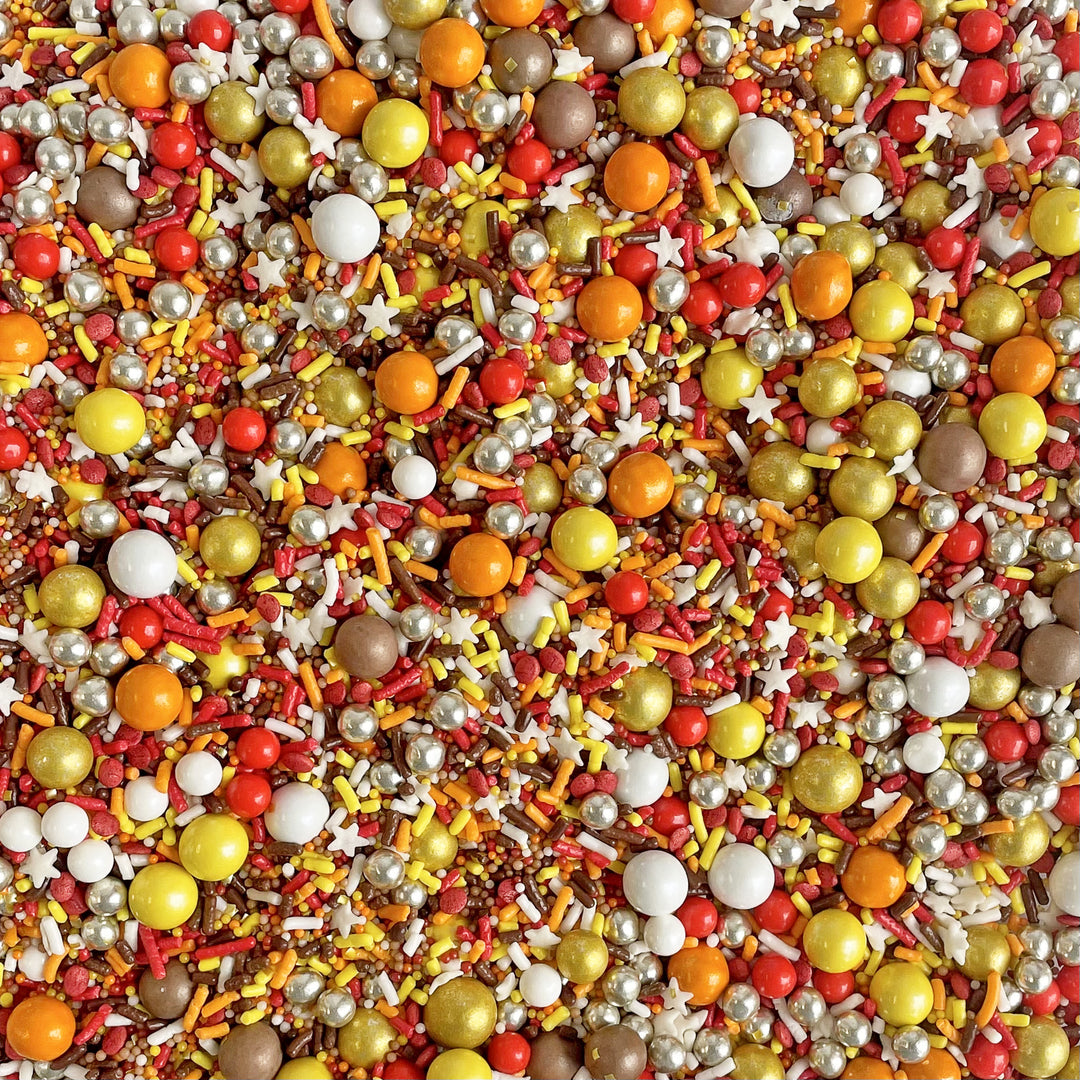 Close-up of Thanksgiving Sprinkle Mix - a blend of classic fall tones in red, orange, yellow, and brown, adorned with chocolate crispy dragees.