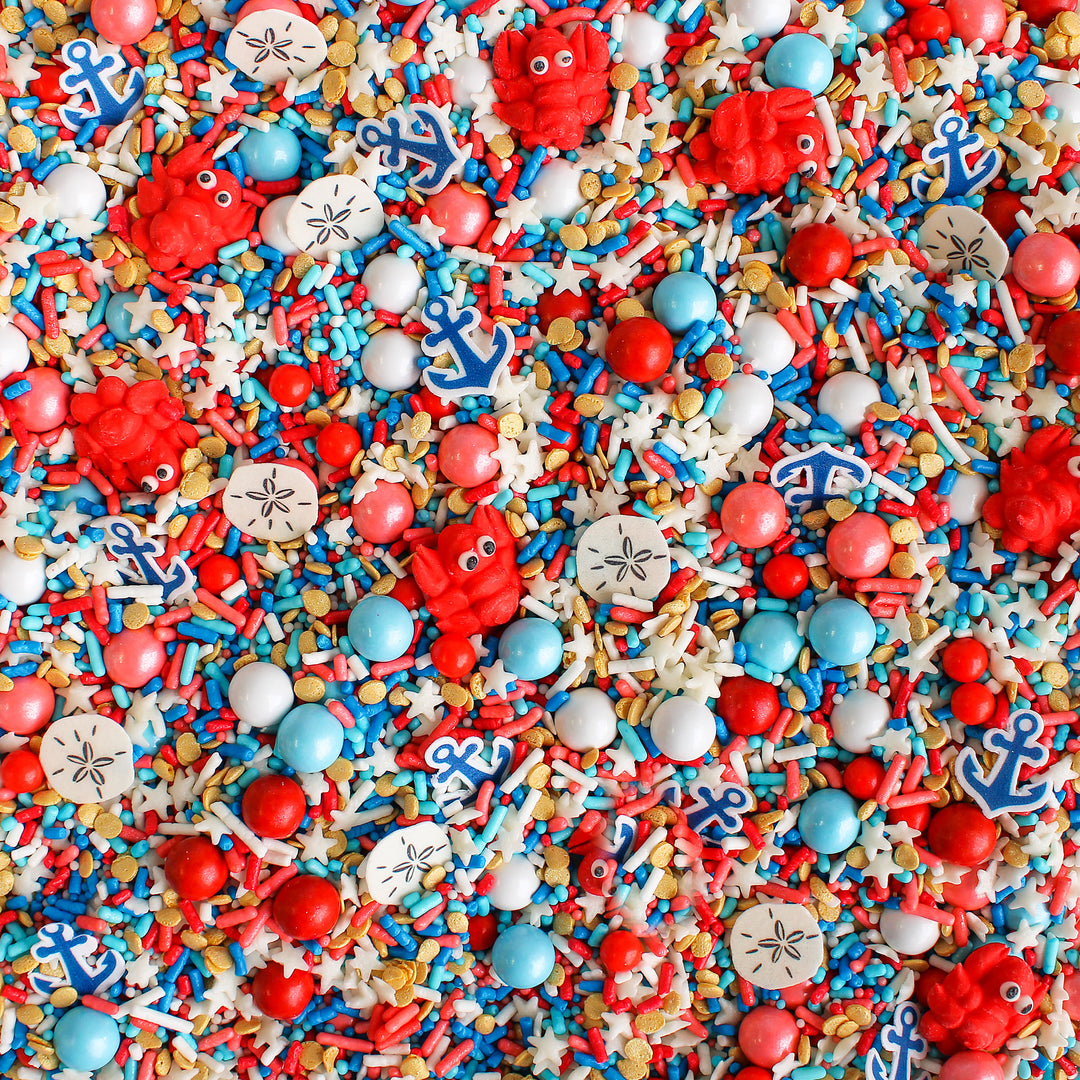Cape Cod Sprinkle Mix with blue, red, white, and gold sprinkles, as well as royal icing lobsters, wafer sand dollars, and wafer anchors.