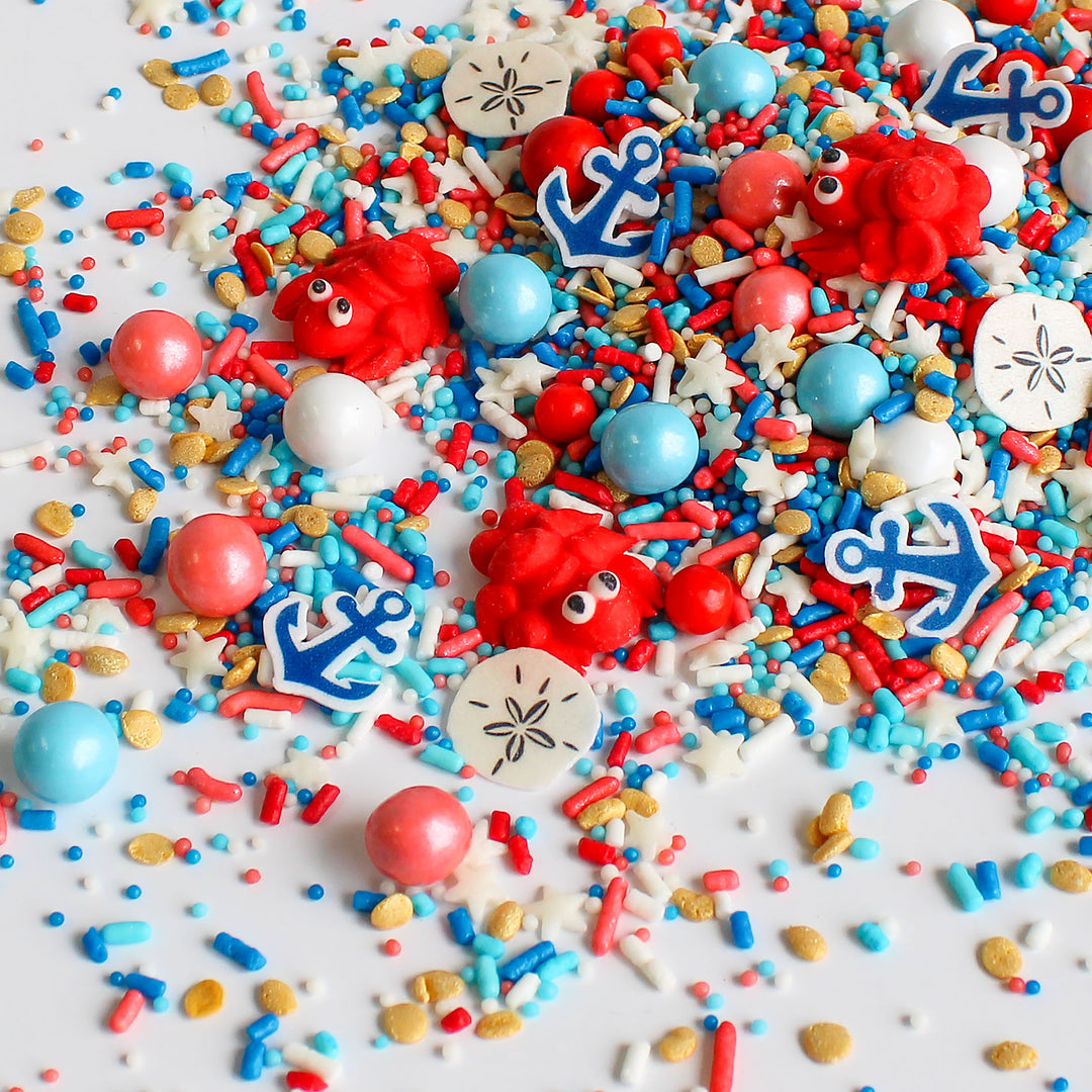 Cape Cod Sprinkle Mix with blue, red, white, and gold sprinkles, as well as royal icing lobsters, wafer sand dollars, and wafer anchors.