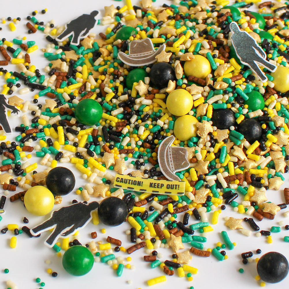 Close-up of Dead Man Walking Sprinkle Mix - a haunting blend of green, yellow, black, and brown sprinkles with wafer zombie silhouettes, sheriff's hat and badge, caution tape, and gold stars.