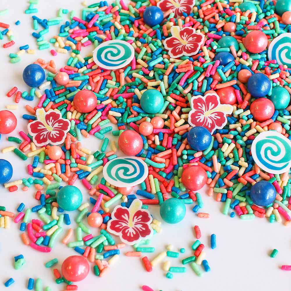 Voyager Sprinkle Mix - A mix of vibrant blue, pink, and teal sprinkles with wafer swirls and tropical flowers.