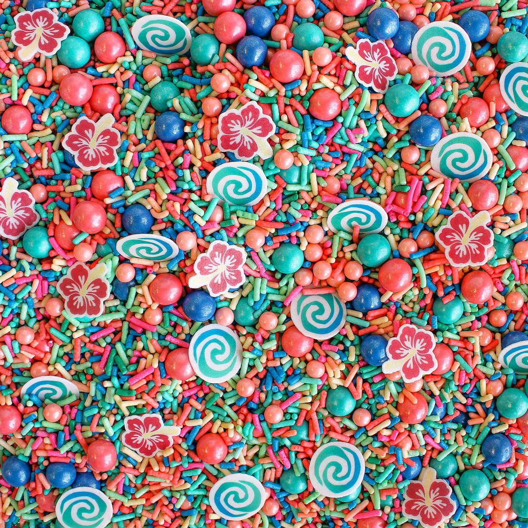 Voyager Sprinkle Mix - A mix of vibrant blue, pink, and teal sprinkles with wafer swirls and tropical flowers.