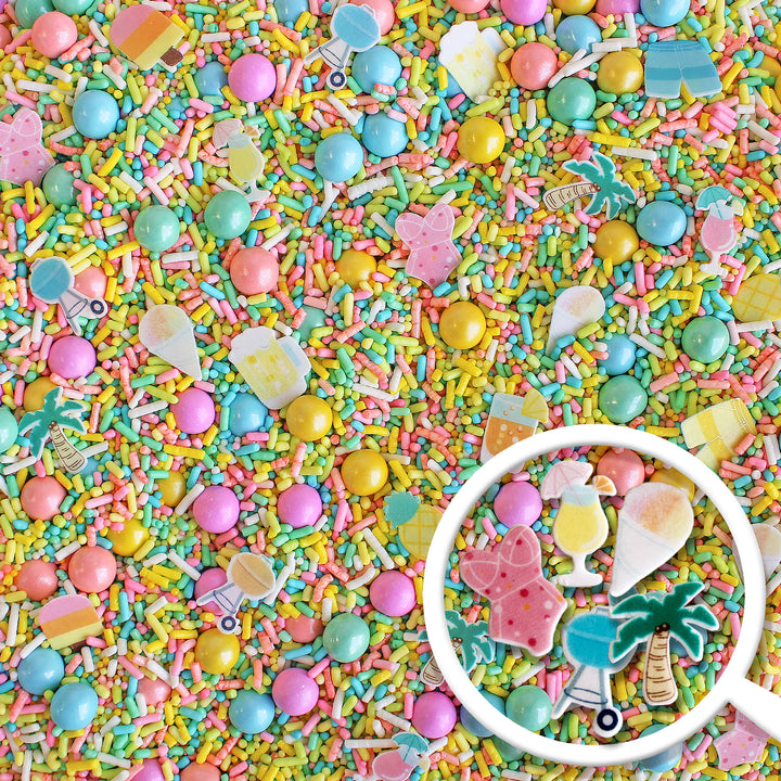 A close-up photo of Palm Springs Sprinkle Mix with a variety of colorful sprinkles, including specialty pieces like wafer swimsuits, palm trees, snow cones, umbrella drinks, and bbq grills. Perfect for decorating cakes, cookies, cupcakes, and even ice cream!