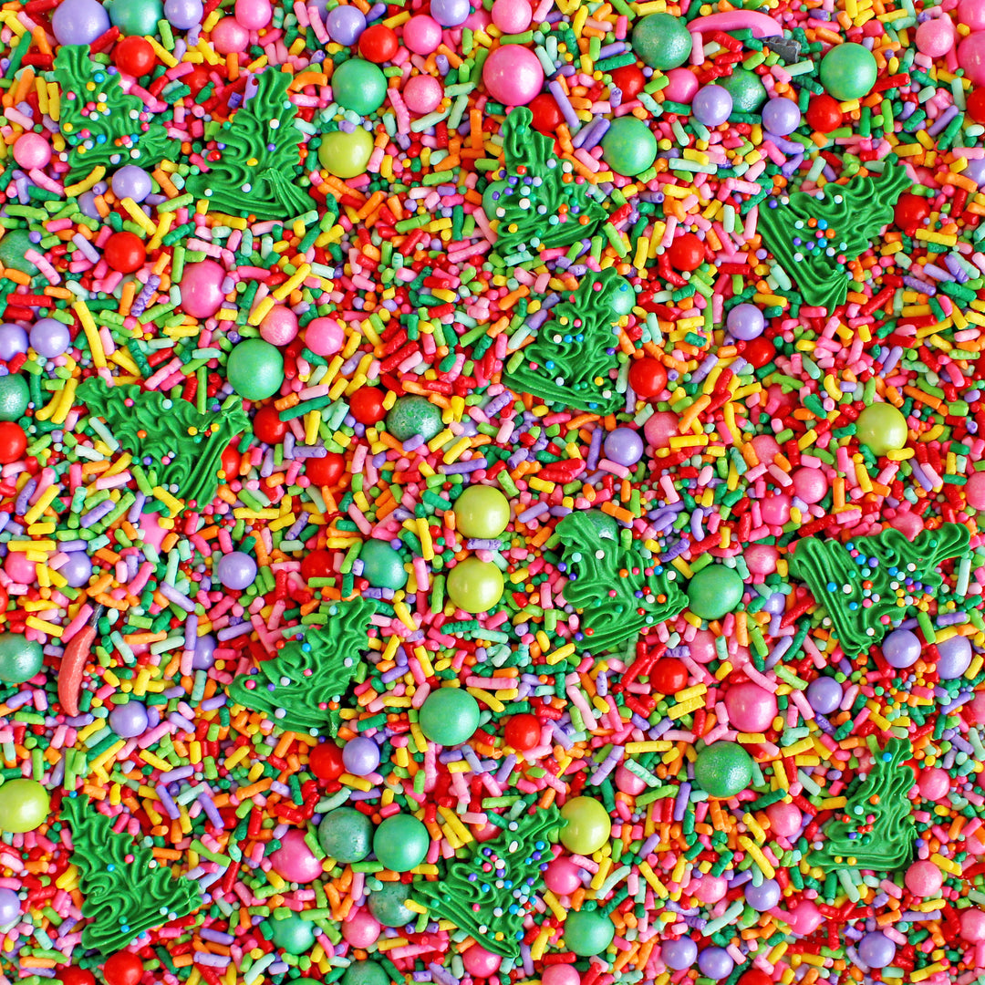 A close-up of Twinkling Trees Sprinkle Mix showcasing a burst of bright Christmas rainbow colors with royal icing Christmas trees for festive cake decorating.