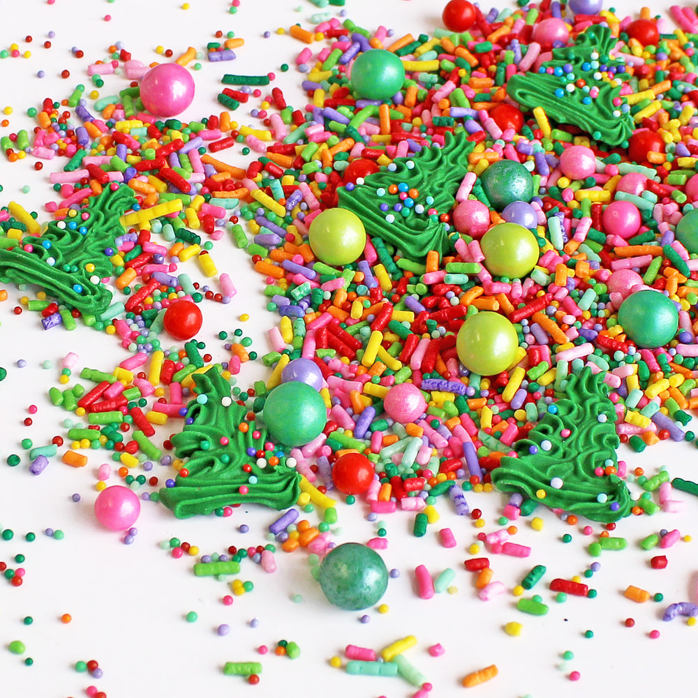 A close-up of Twinkling Trees Sprinkle Mix showcasing a burst of bright Christmas rainbow colors with royal icing Christmas trees for festive cake decorating.