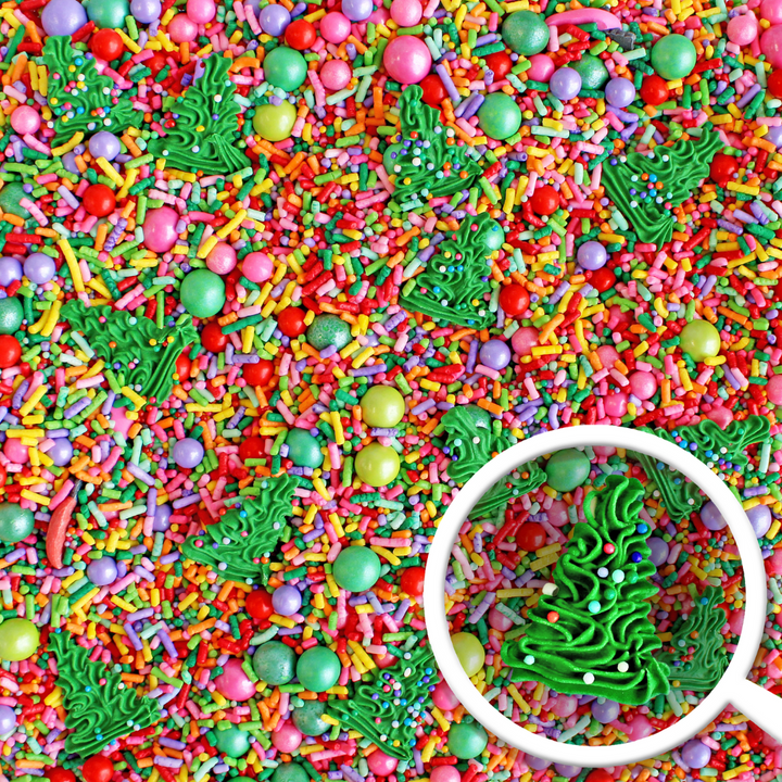 A close-up of Twinkling Trees Sprinkle Mix showcasing a burst of bright Christmas rainbow colors with royal icing Christmas trees for festive cake decorating.