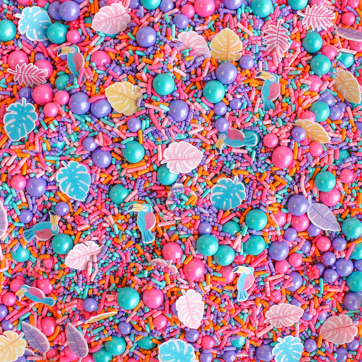 Birds In Paradise Sprinkle Mix - A vibrant blend of aqua, pink, purple, and orange sprinkle shapes with tropical birds and palm fronds.