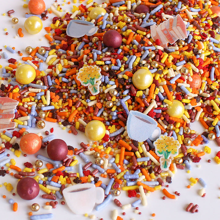 Dragonfly Hollow Sprinkle Mix - A blend of gold, burgundy, orange, and dusty blue sprinkles with wafer flowers, books, and a cup of coffee.