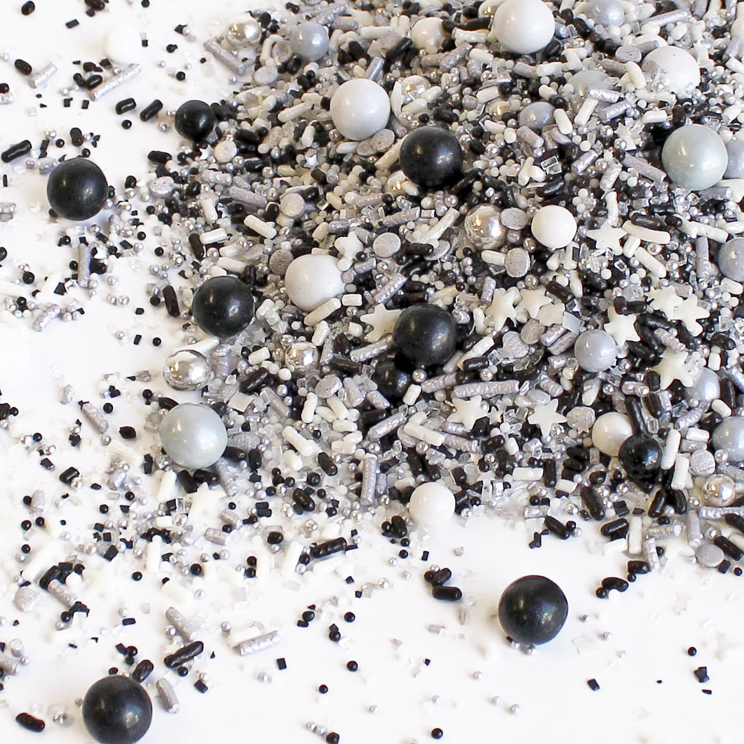 A refined dessert adorned with Black Tie Sprinkle Mix, featuring black, white, and silver metallic sprinkles, adding an elegant touch to the celebration.