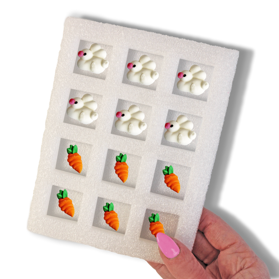 Image of hand-piped royal icing bunny and carrot decorations, with six of each design included in the set. The decorations are approximately 0.75 inches in size and are ideal for use as cupcake, cookie, or cake decorations. The set features vibrant colors and has a shelf life of 5 years.