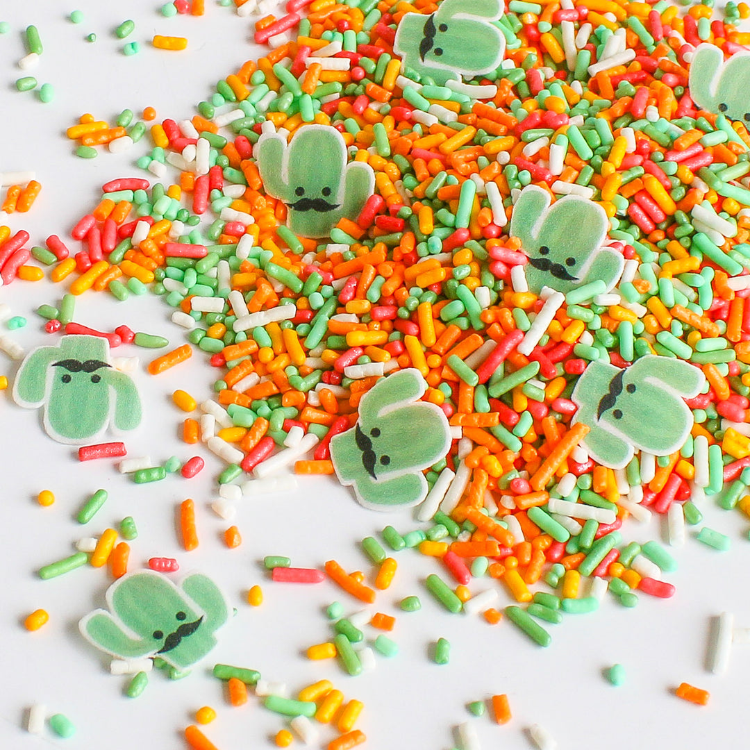A close-up image of a sprinkle mix with various shapes and colors, including edible cactus-shaped wafers. The image is colorful and fun, perfect for adding to baked goods.
