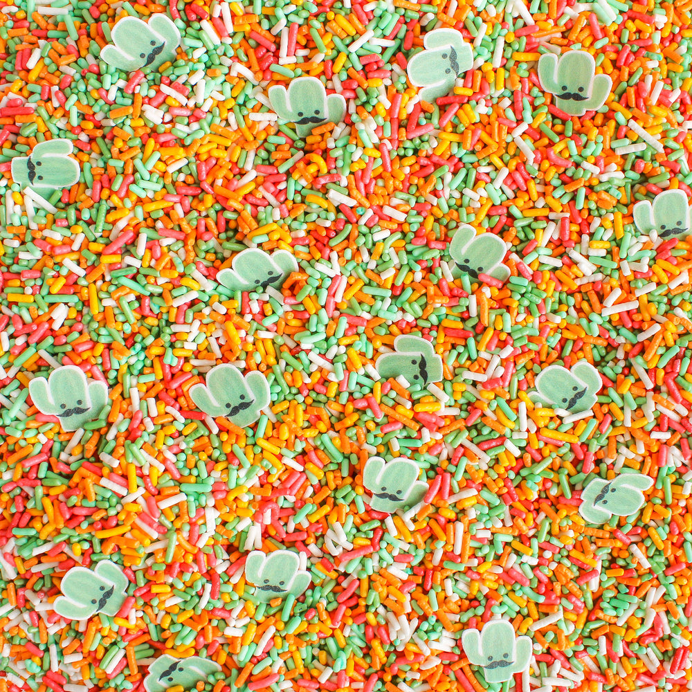A close-up image of a sprinkle mix with various shapes and colors, including edible cactus-shaped wafers. The image is colorful and fun, perfect for adding to baked goods.