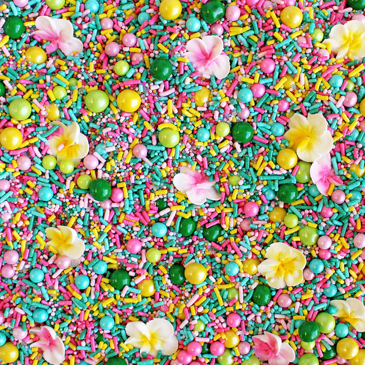 A photo of a sprinkle mix with tropical colors and hand-piped royal icing plumerias.
