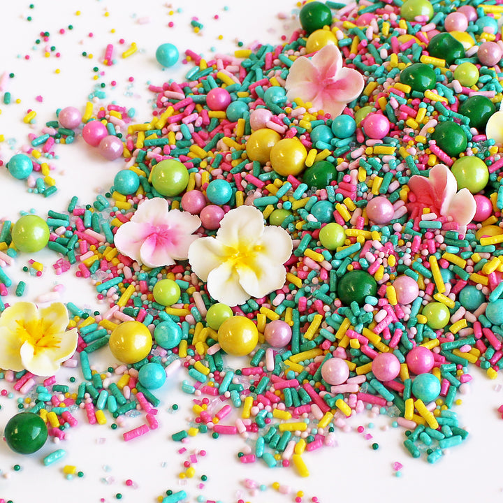 A photo of a sprinkle mix with tropical colors and hand-piped royal icing plumerias.