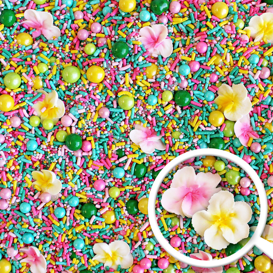 A photo of a sprinkle mix with tropical colors and hand-piped royal icing plumerias.