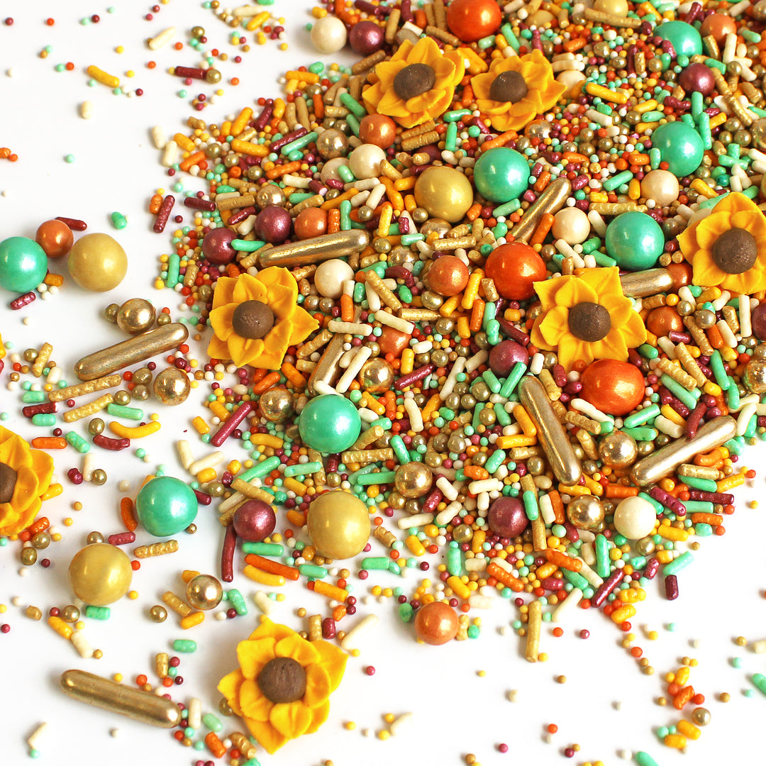 Close-up of Sunflower Sprinkle Mix - a blend of warm burgundy, golden yellow, orange, and a vibrant mint, adorned with hand-piped royal icing sunflower sprinkles.