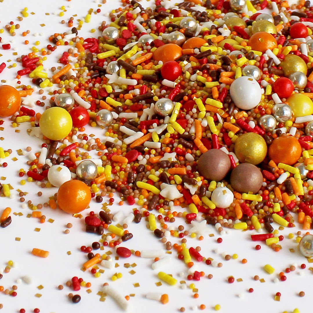 Close-up of Thanksgiving Sprinkle Mix - a blend of classic fall tones in red, orange, yellow, and brown, adorned with chocolate crispy dragees.