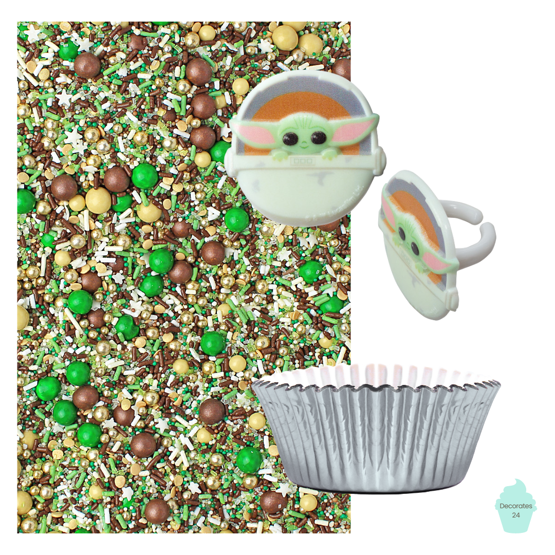 A photo of a silver cupcake with a Baby Yoda cupcake ring on top, surrounded by "The Force" green, gold, and brown sprinkle mix and silver cupcake liners. 
