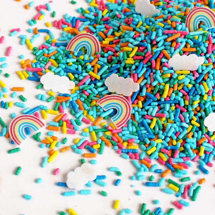 An image of "You're My Rainbow" Sprinkle Mix in a clear plastic container with a colorful burst of rainbow sprinkles, wafer paper clouds, and rainbows on top. The packaging features the words "You're My Rainbow" in playful, whimsical font.